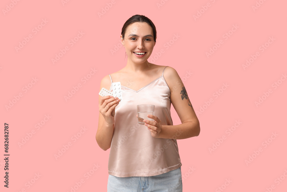 Beautiful young woman with condom and birth control pills on pink background. Safe sex concept Beautiful young woman with condom and birth control pills on pink background. Safe sex concept