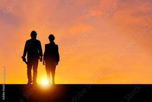 Silhouette of Engineer and foreman worker with blurred sunset in evening time background, construction concepts