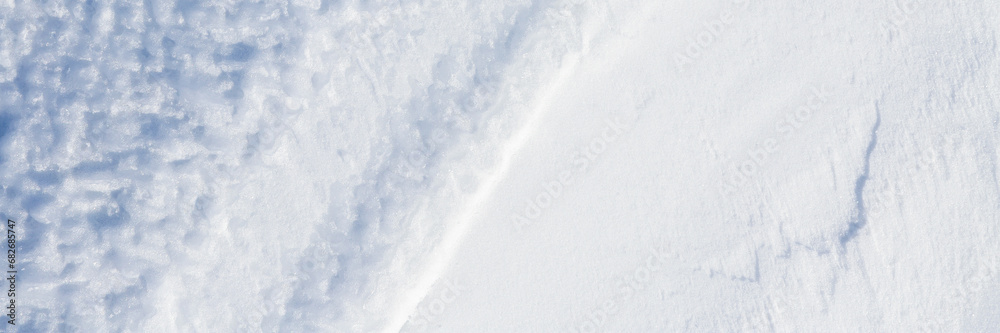 Obraz premium Beautiful winter background with snowy ground. Natural snow texture. Wind sculpted patterns on snow surface. Wide panoramic texture for background and design.