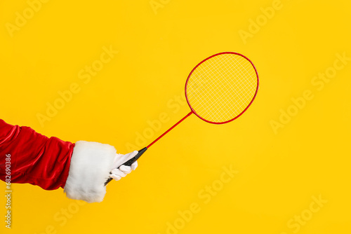 Santa hand with badminton racket on yellow background © Pixel-Shot