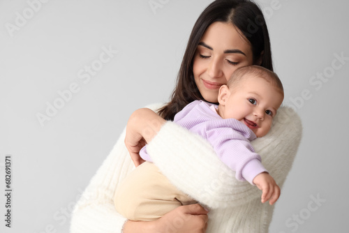 Happy mother with her little baby on light background