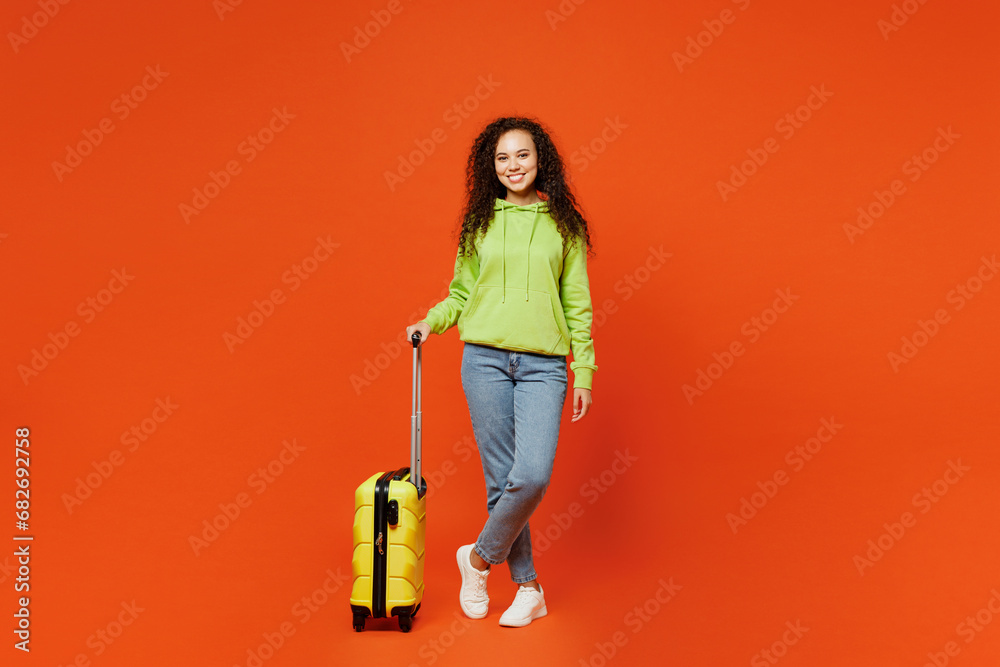 Full body traveler happy fun woman wears casual clothes hold suitcase bag isolated on plain orange background. Tourist travel abroad in free spare time rest getaway. Air flight trip journey concept. Full body traveler happy fun woman wears casual clothes hold suitcase bag isolated on plain orange background. Tourist travel abroad in free spare time rest getaway. Air flight trip journey concept.