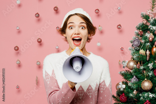 Merry young woman wear white sweater hat posing hold in hand megaphone scream announces discounts sale Hurry up isolated on plain pink background. Happy New Year celebration Christmas holiday concept.