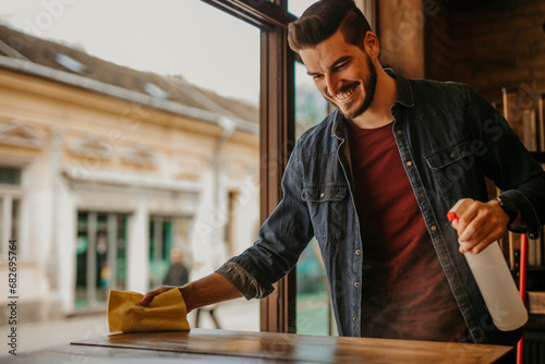 Quadro em tela A restaurant owner ensuring tables are squeaky clean with a trusty spray