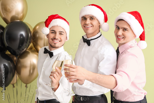 Male friends with champagne on green background. New Year celebration