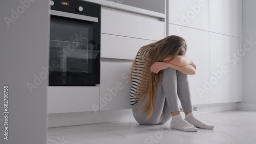 Upset woman, disappointed by problems in family relationships, sits and hugs her knees, covers her face in her hand. photo