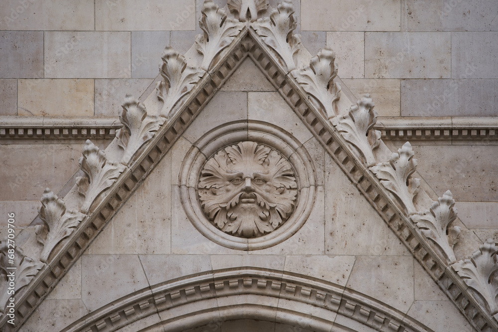 Obraz premium Bas relief of a face turned to stone on a facade of the Hungarian Parliament Building (Hungarian: Országház). Budapest, Hungary - 7 May, 2019