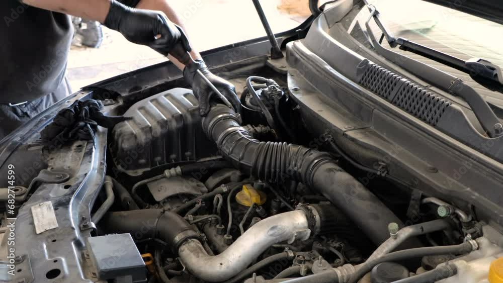 Mechanic man is screwing the car engine air filter pipe with a screwdriver in his hand. vehicle maintenance service Mechanic man is screwing the car engine air filter pipe with a screwdriver in his hand. vehicle maintenance service