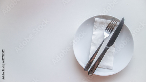 Dinner place setting. White empty plate , silver fork and knife on white background, top view, copy space