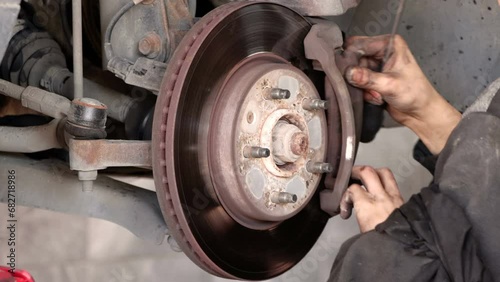 Disk brake pad and car disk brake system change service. Car disk brake pad replacement service by hand of mechanic man in car garage. Process of replacing brake pads with new. Dirty hands no glove