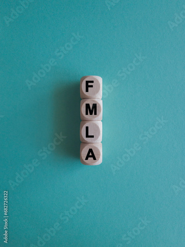 FMLA family medical leave act symbol. Concept words FMLA family medical leave act on wooden cubes. Beautiful blue background.