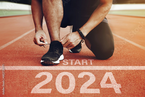 Athletes are getting ready to run on the track with the text  2024 in New Year's Start concept. start the new year 2024 and reach new goals and achievements. planning, challenges, new year resolution. photo