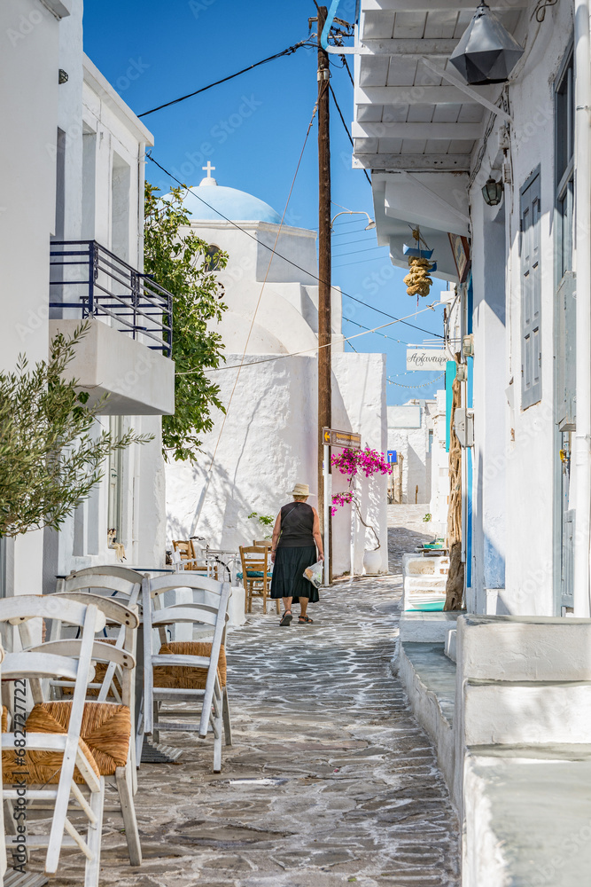 Fototapeta premium Elderly woman dressed in black walking in a typical alley of Chorio village, Kimolos island GR
