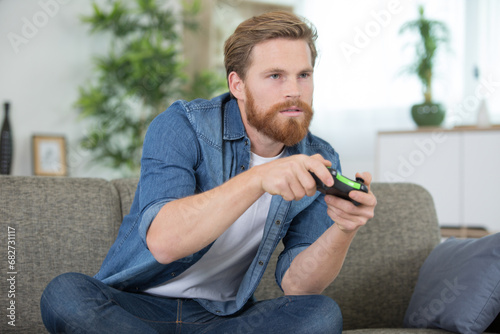 concentrated man sitting on a sofa and playing computer games