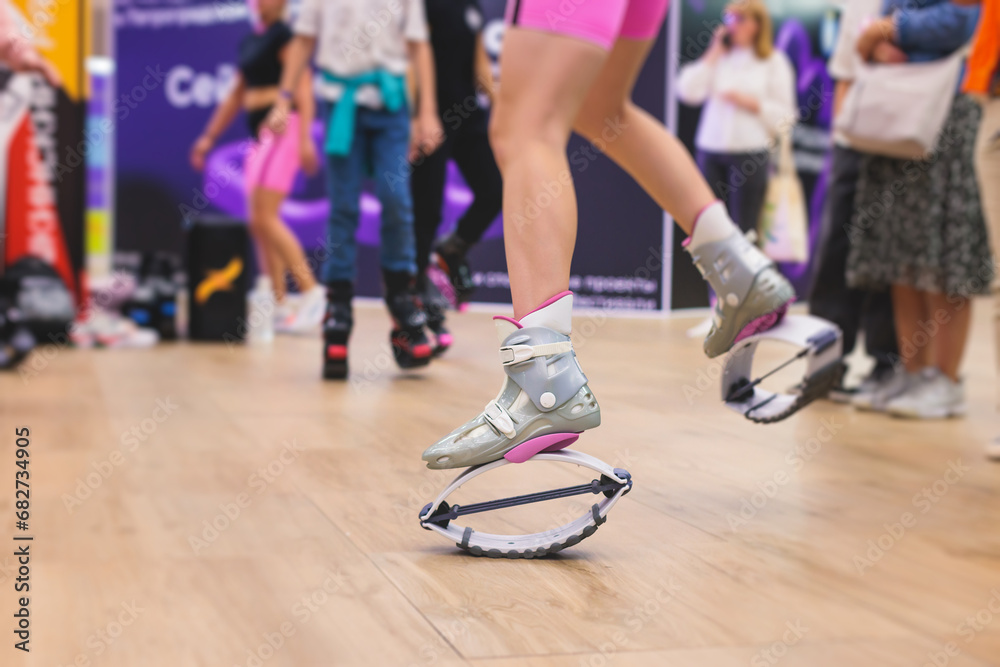 Kangoo shoes, fitness jumping training, group of young fit women in sportswear on kangoo jumps, girls training with coach instructor, exercising at the gym with jump foot wear shoes, fitness studio