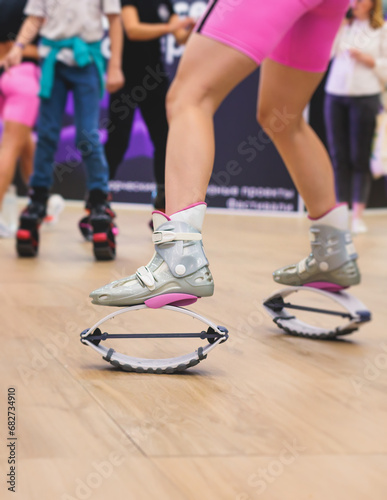 Kangoo shoes, fitness jumping training, group of young fit women in sportswear on kangoo jumps, girls training with coach instructor, exercising at the gym with jump foot wear shoes, fitness studio