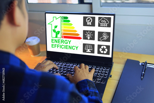 Man working with home energy rating label on laptop computer screen to select most highest efficiency residential to save energy cost and less co2 emission photo