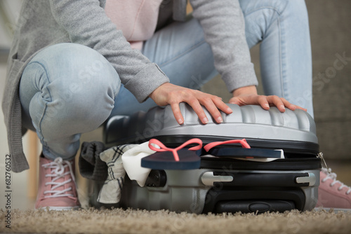 cropped view of woman cramming closed her suitcase photo