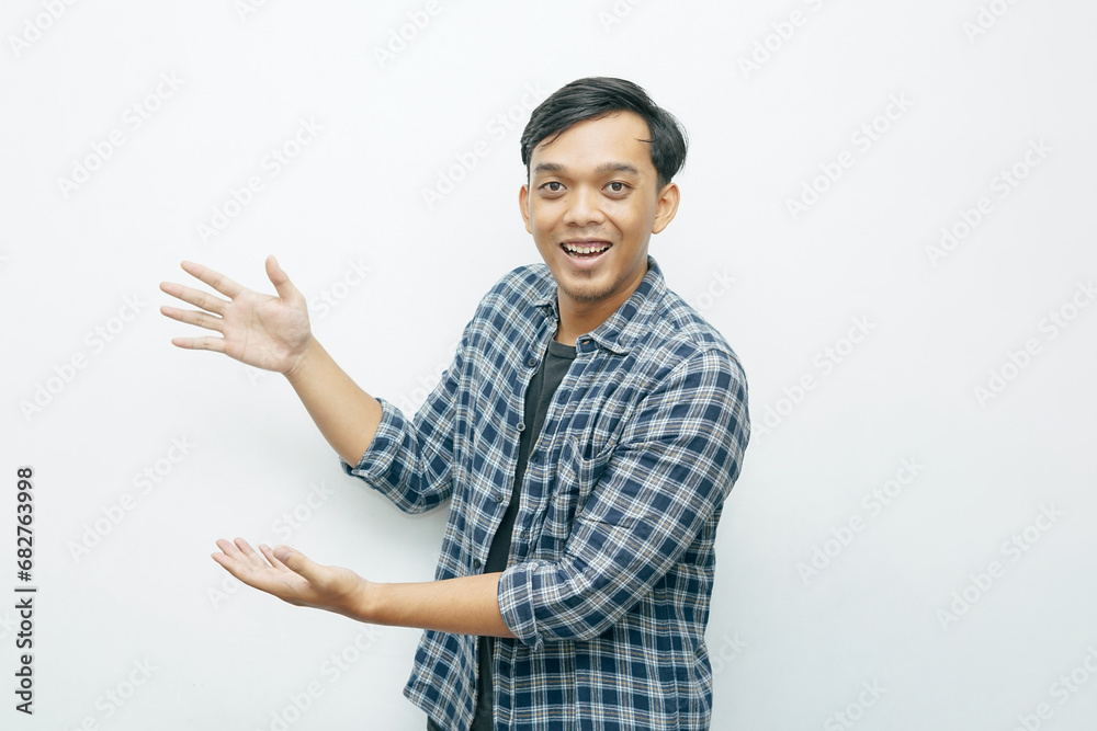 Portrait of young Indonesian Asian man smiling while put hands in side of his body for presenting something gesturing Portrait of young Indonesian Asian man smiling while put hands in side of his body for presenting something gesturing