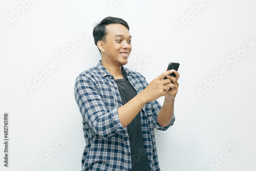Portrait of Indonesian Asian man smiling when holding smartphone. Isolated white background