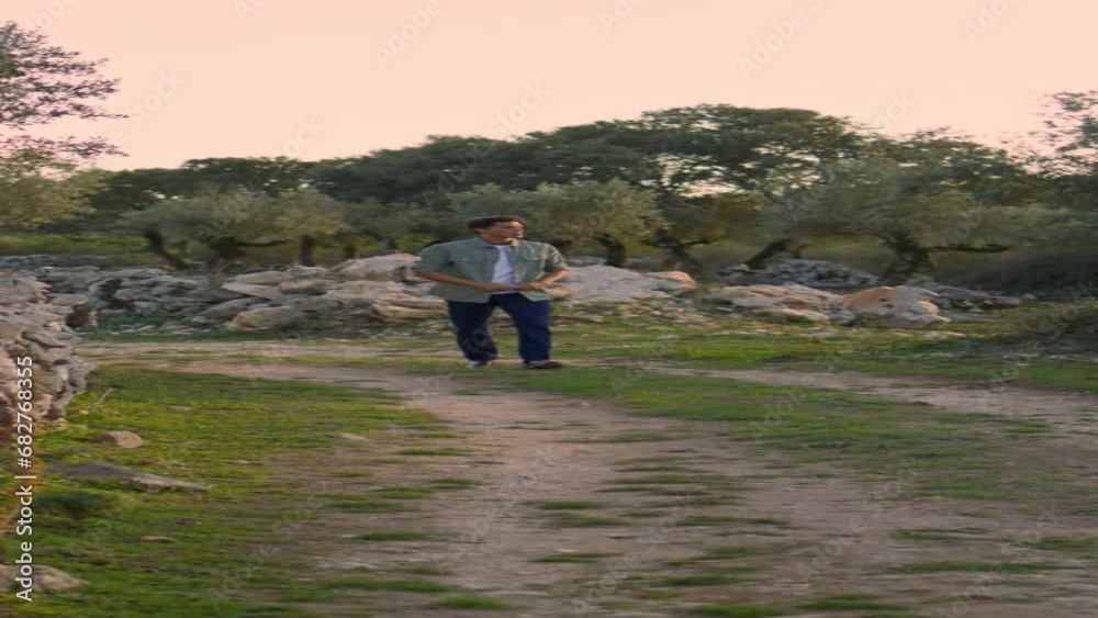 Tanned guy observing garden nature alone. Serious man crossing path vertically Tanned guy observing garden nature alone. Serious man crossing path vertically