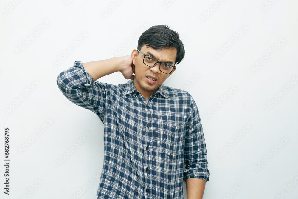 Portrait of Asian Indonesian man put his hands on neck for feeling pain gesture. Isolated white background Portrait of Asian Indonesian man put his hands on neck for feeling pain gesture. Isolated white background