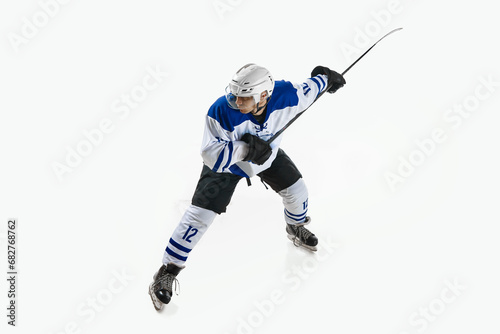 Man, ice hockey player in motion during game with stick, training, playing against white studio background