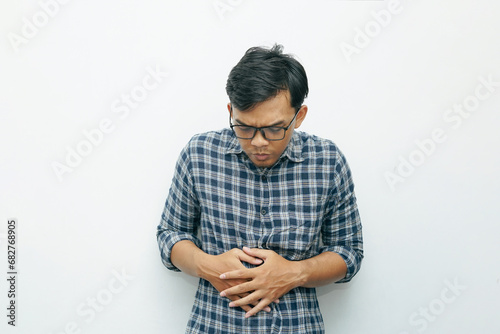 Portrait of Asian Indonesian man placing his hands on stomach for stomach ache or hungry gesture