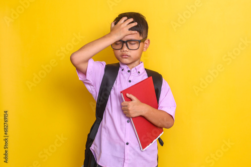 Fotografi Forgetful Asian boy touching forehead while hold books at school