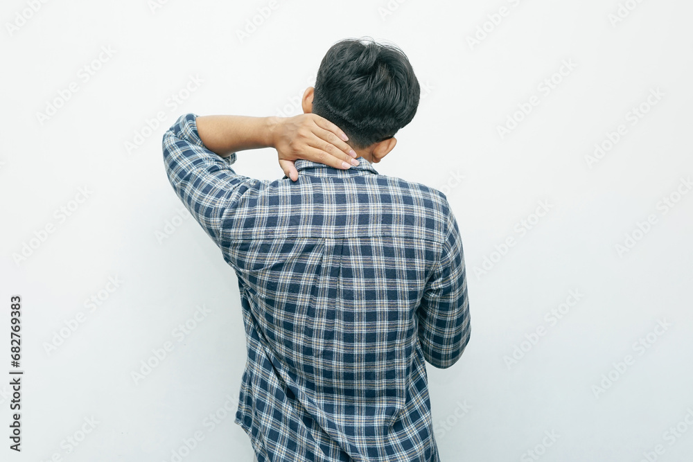Portrait of Asian Indonesian man put his hands on neck for feeling pain gesture. View from behind isolated white background Portrait of Asian Indonesian man put his hands on neck for feeling pain gesture. View from behind isolated white background