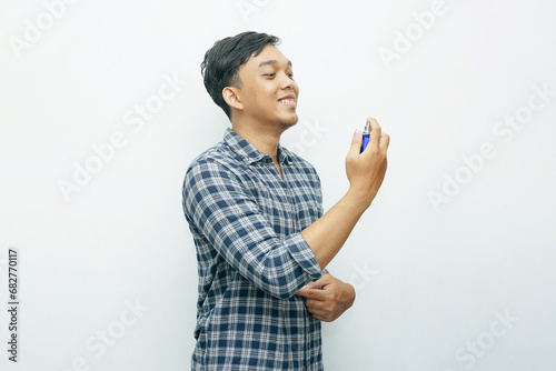 Portrait Asian Indonesian young man spraying perfume to his body photo