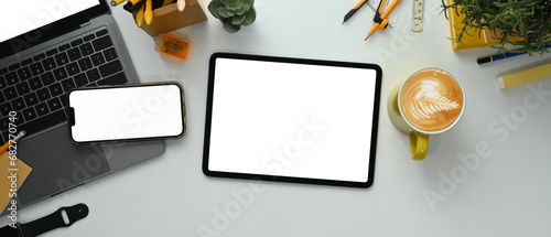 Modern workplace with digital tablet, smartphone, laptop, coffee cup and stationery on white table photo