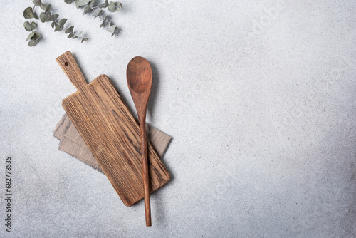 Foto Cutting board with wooden kitchen spoons and linen napkin