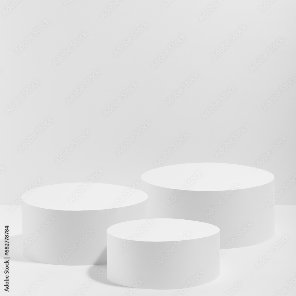 Abstract white stage with three white round podiums mockup for cosmetic products in hard light on white background. Scene for presentation cosmetic products, gifts, goods, advertising, design, sale. - obrazy, fototapety, plakaty 