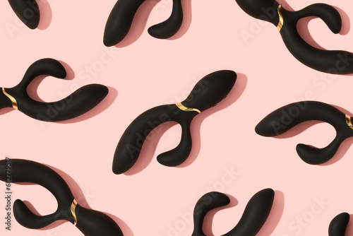 Black vibrator on the peach pink background. Sex toys for adults. Pattern