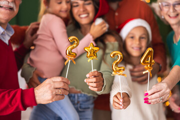Family celebrating New Year holding little balloons shaped as numbers 2024