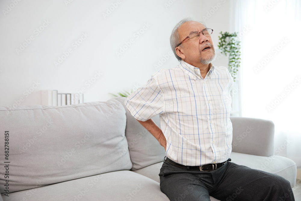 senior man suffering from back pain on sofa