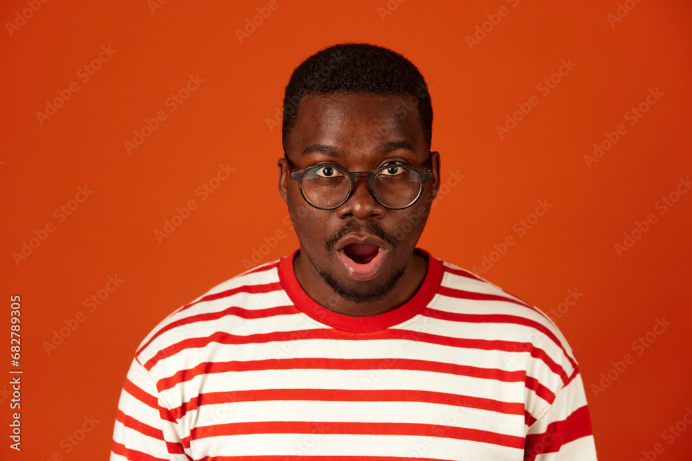 Shocked or surprised African-American man with open mouth on orange background Shocked or surprised African-American man with open mouth on orange background