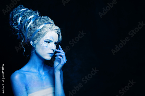 Nice cool cold woman with blue and white body art, carnival makeup and hairstyle on black background photo