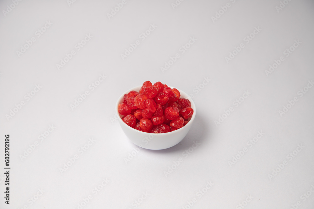 Dried red cherry fruit on white bowl with white background, Dried cherries scattered on the white background in a black bowl or vessel Dried red cherry fruit on white bowl with white background, Dried cherries scattered on the white background in a black bowl or vessel