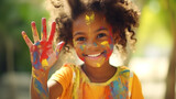 An African American child with her palm and face are stained with colorful paints. Happy young artist with paint-stained hand