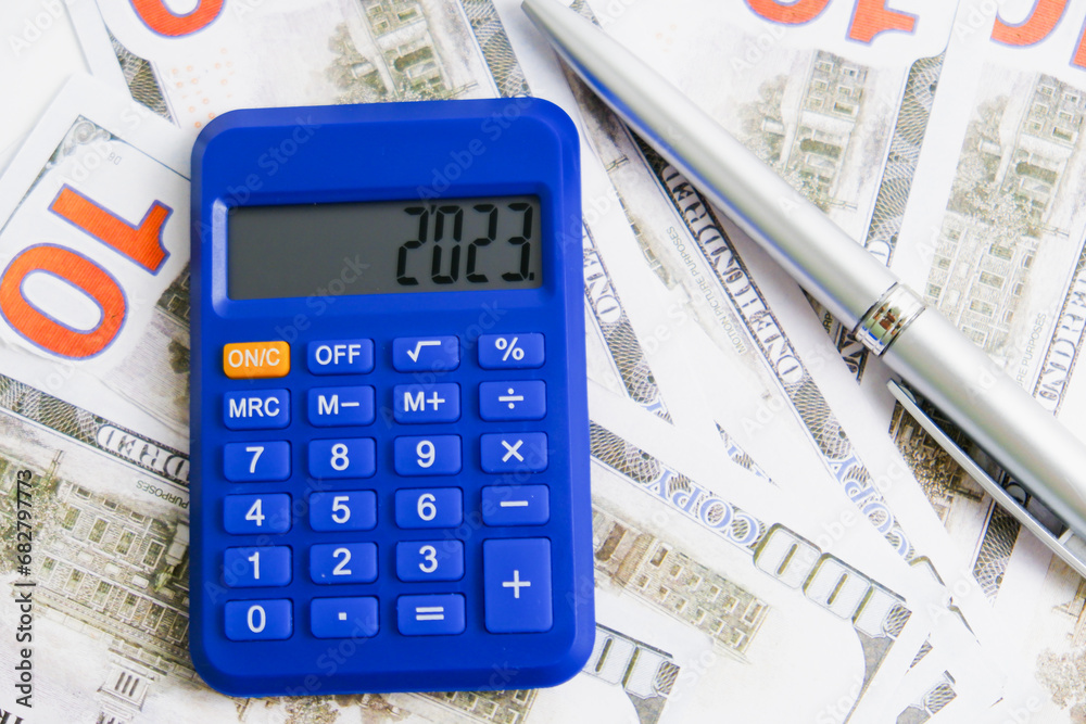 A calculator with display 2023, money and pen. Accounting conceptual. A calculator with display 2023, money and pen. Accounting conceptual.