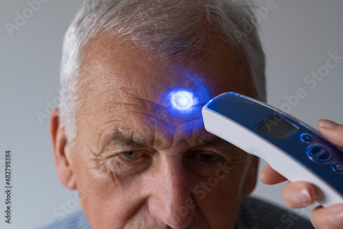 The nurse measures the temperature of a senior. photo