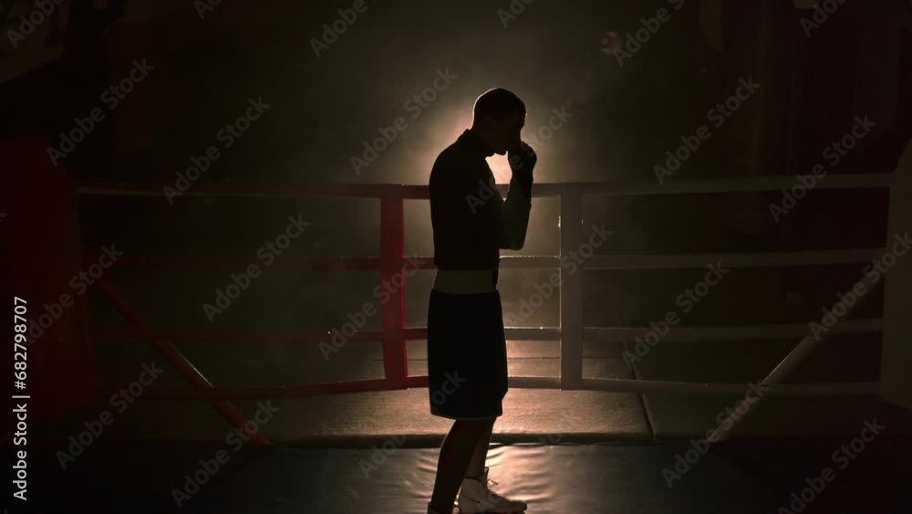 Boxer doing warm-up exercises in a boxing ring against a background of smoke
