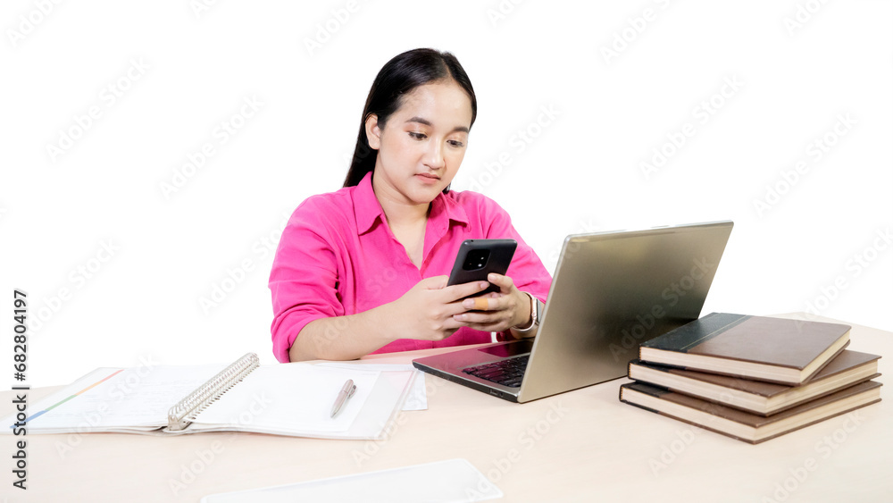 Female student using mobile phone while studying with a laptop computer and books Female student using mobile phone while studying with a laptop computer and books