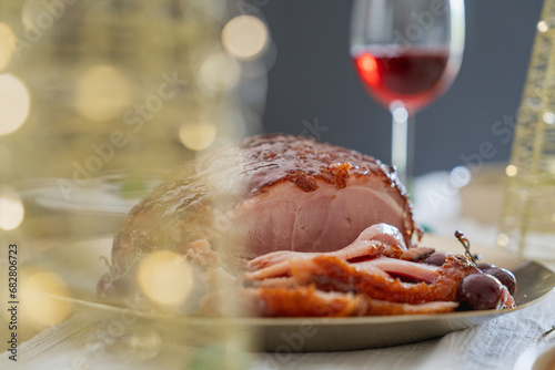 Christmas composition with baked Christmas ham or gammon on dark background. Traditional food concept. Plate with delicious ham served on wooden table, closeup. Christmas dinner.