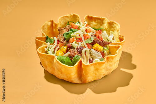 Taco salad in tortilla bowl with beef, cheese, corn and lettuce photo