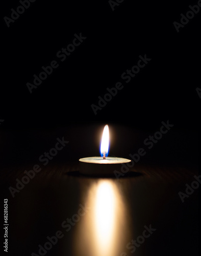 One candle light burning brightly in the black background.