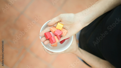 Top close up view of white hands showing colorful candies in a park with left copy space