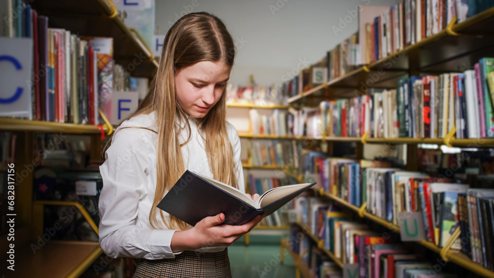 Teenage girl taking a book from a bookshelf in the school library. Education learning concept. Teenage girl taking a book from a bookshelf in the school library. Education learning concept.